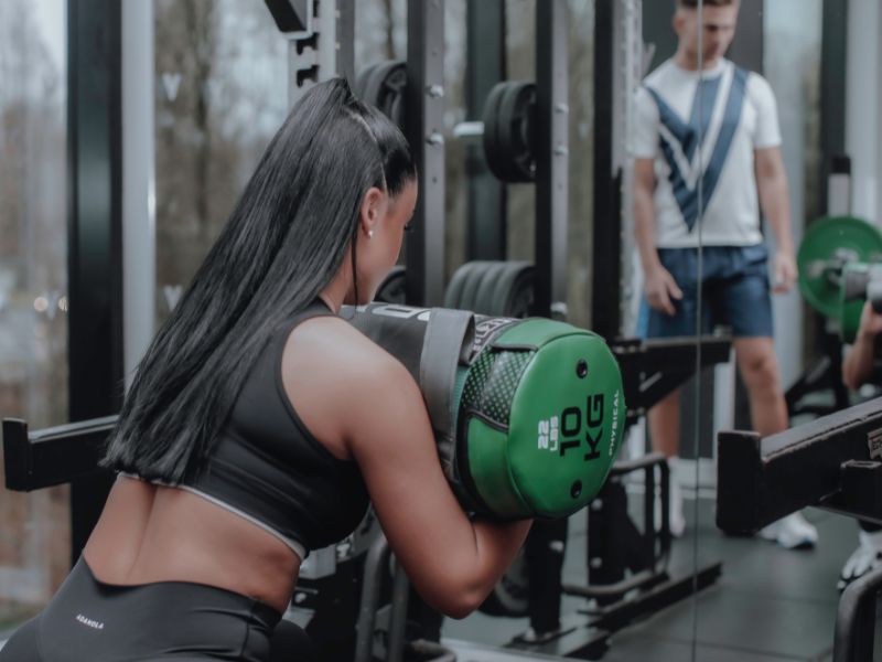 A personal trainer instructs a woman during a workout session in a gym setting.