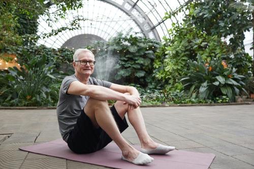 Senior man sits on exercise mat